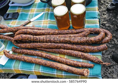Sale of homemade sausages and honey out on the table.
