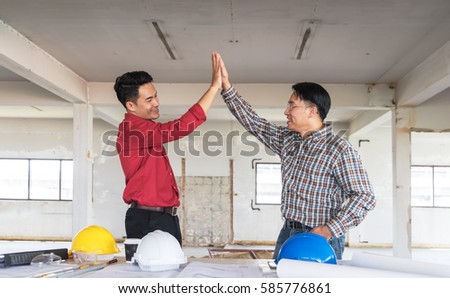 Two engineer men meeting in construction site, doing hand tagged as hi five with right hand. teamwork success project concept