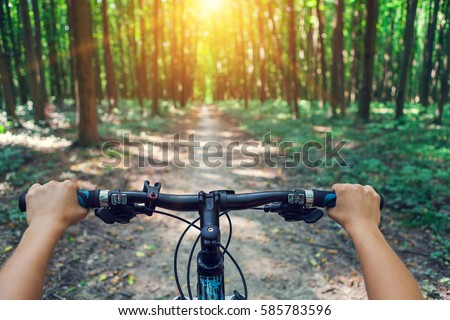 Mountain biking down hill descending fast on bicycle. View from bikers eyes. Royalty-Free Stock Photo #585783596