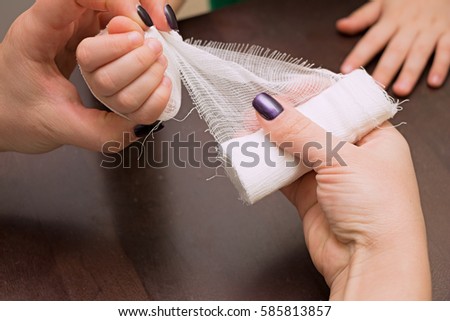 Woman makes a bandage on a child's hand