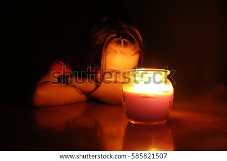 Portrait of little girl at night staring at lit glowing candle