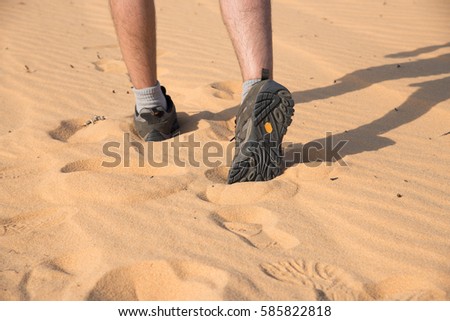 A man walking on sand dune with hiking shoes and foot print Royalty-Free Stock Photo #585822818