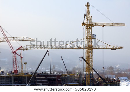 Workers are building a building by means of a tower crane