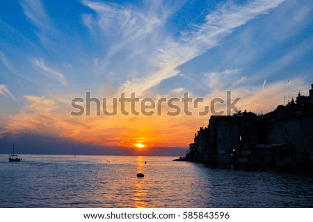 Stunning sunset with water reflection and blue sky with clouds with silhouette old town background, seacoast Croatia.