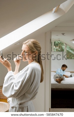 Young woman applying make up in bathroom