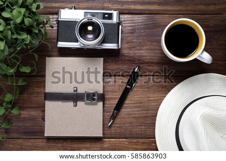 note book with old camera and coffee on wood desk , top view