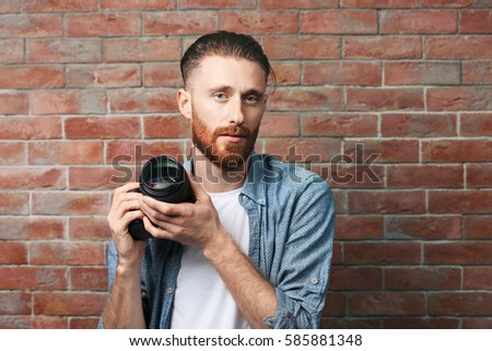 Handsome photographer near brick wall