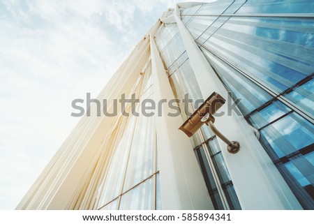 Single surveillance camera on facade of contemporary business skyscraper on sunny summer day, security camera on metal beam of modern office building with copy space for your logo or message text Royalty-Free Stock Photo #585894341