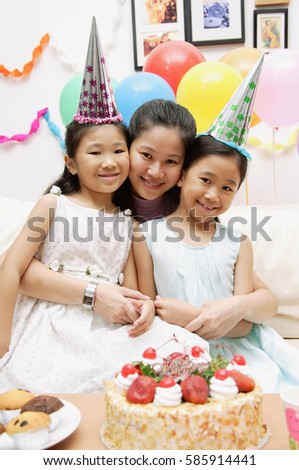 Mother with two girls celebrating a birthday, smiling at camera