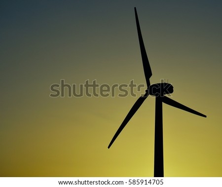Wind turbine backlit with intense color background at dawn