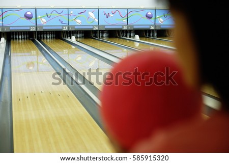 Woman holding bowling ball, preparing to bowl, over the shoulder view