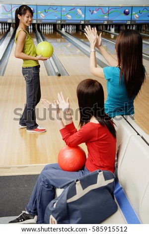 Women in bowling alley, cheering friend on