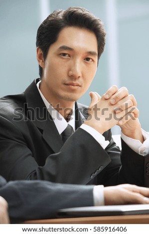 Businessman looking at camera, hands clasped