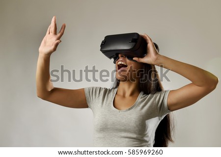 young attractive happy woman excited using 3d goggles watching 360 virtual reality vision enjoying cyber fun experience in vr simulation reality and new gaming technology isolated grey background