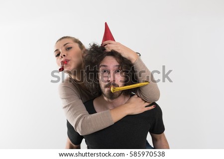 Young happy couple in party hats blowing in whistle isolated on a white background