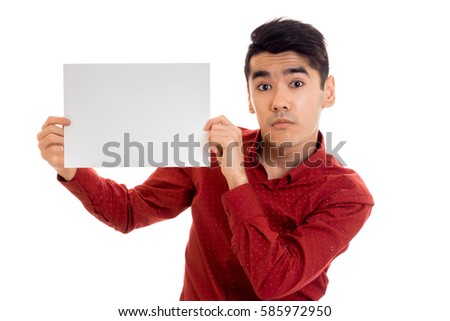 surprised young stylish male model posing in red shirt with empty placard isolated on white background