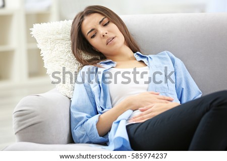 Young woman suffering from abdominal pain at home. Gynecology concept Royalty-Free Stock Photo #585974237