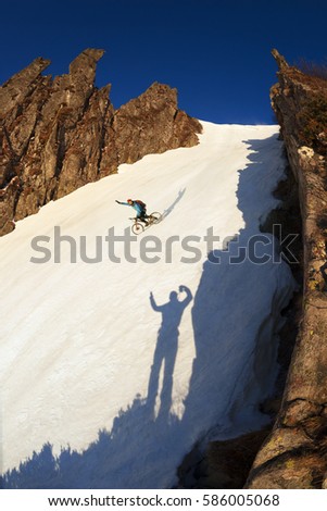 sportsman racer, mountain bike carbon spring rolls on the winter snow on a background of the beautiful peaks rocks tops in Black Mountain ridge in Carpathians, Ukraine

