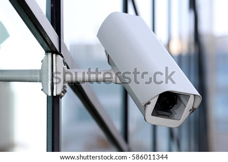 white security cctv camera on glass facade