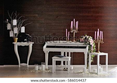 Composition with white piano and candles, candlesticks and rose petals