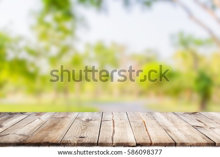 Empty wooden table with garden bokeh for a catering or food background with a country outdoor theme / Template mock up for display of product Royalty-Free Stock Photo #586098377