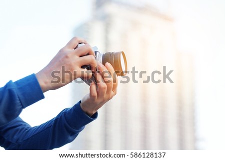woman holding film camera taking photograph in the city