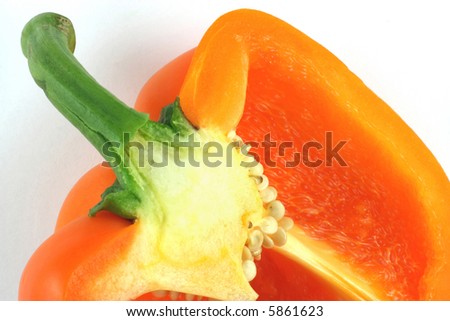 Orange organic pepper. Close up picture of cut on half orange organic pepper over white background. Well seen are the seeds and structure of the paper wall.