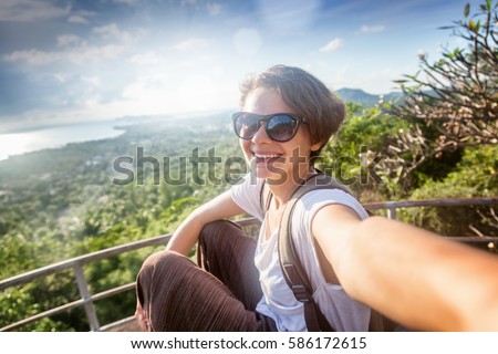 young woman traveler in sunglasses makes selfie with sea view