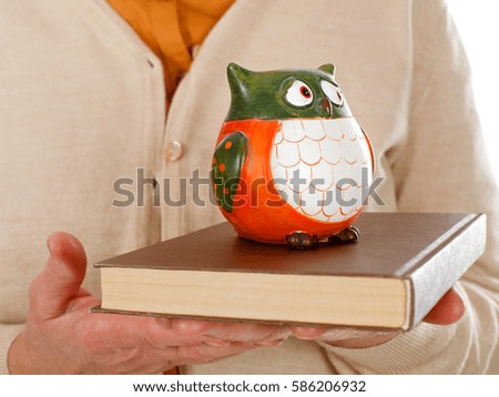Close up picture of an elderly woman holding a book and an owl as the symbol of wisdom