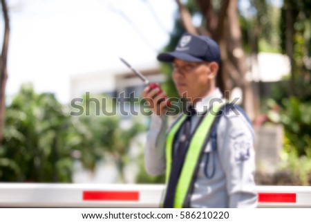 Portrait Of Asian Male Security Guard Talking a portable wireless transceiver entrance the village on a blurry background,use a filter