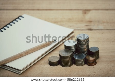 Close up coins and notebook on wood table, business concept, process vintage tone