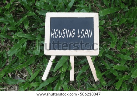 Mini Blackboard with word written 'HOUSING LOAN' on green grass background