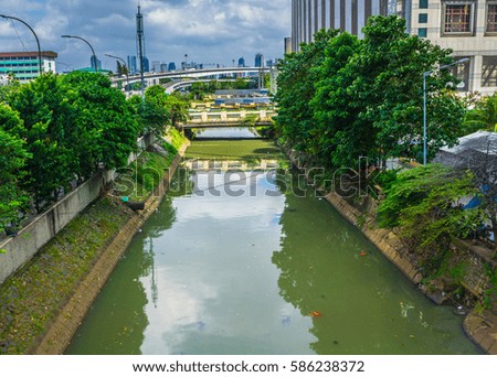 a river in the middle Jakarta near Central Park Mall with reflection of buildings and trees photo taken in Jakarta Indonesia