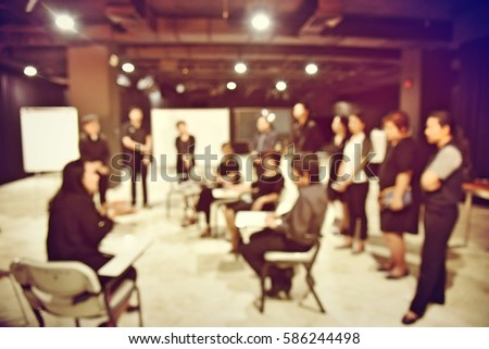 blurred image of production team is sitting and standing, the chairman is talking with the business project in television studio station. vintage filter tone colour