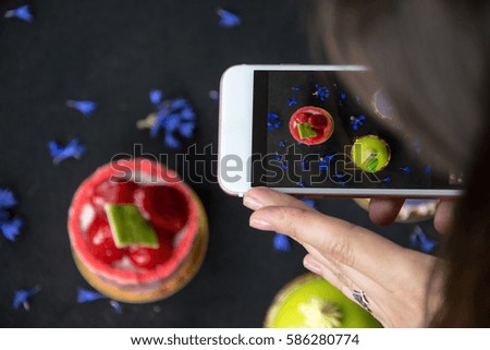 Young woman taking picture of french mousse cake  with smartphone. Mobile photographer