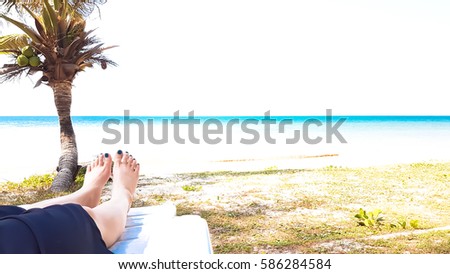 Girl's leg lay on white armchair in the beach with sea view and coconut tree Abstract
