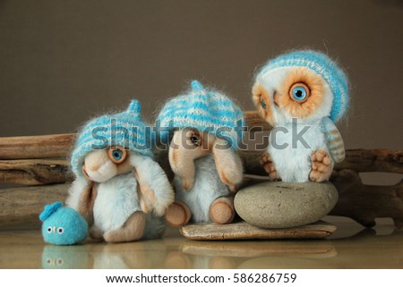 Photo of furry toy animals, owl, elephant, rabbit and a little bird. They are dressed in warm knit hats. Photo illustration is suitable for warm clothing advertising, woolen thread.