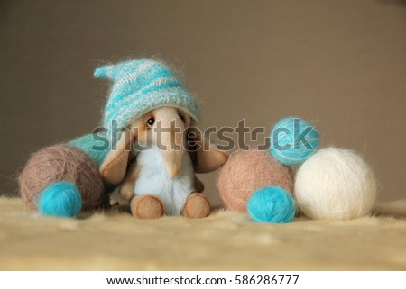 Photo of furry toy elephant  with a balls of wool yarn. They are dressed in warm knit hats. Photo illustration is suitable for warm clothing advertising, woolen thread.