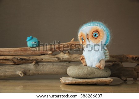 Photo of furry toy animals, owl and a little bird. They are dressed in warm knit hats. Photo illustration is suitable for warm clothing advertising, woolen thread.