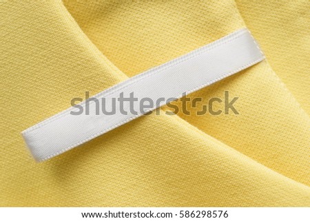 Blank clothes label on yellow cotton as a background