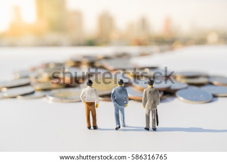 Miniature people: Small businessmen walking to coins road with cityscape background. Business agency marketing and Travelling concepts.