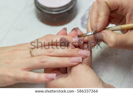 applying a brush on acrylic nails in the salon Royalty-Free Stock Photo #586337366