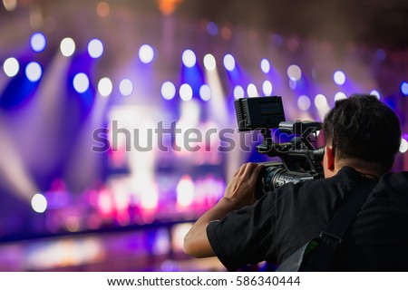 Covering an event on stage with a video camera. Royalty-Free Stock Photo #586340444