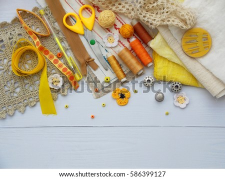 Composition of yellow accessories for needlework on wooden background. Knitting, embroidery, sewing. Small business. Income from hobby.