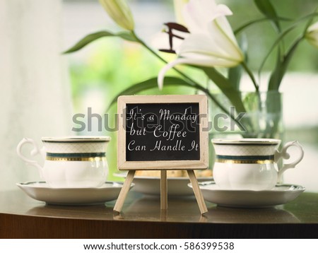 exclusive tea cups and flower on the coffee table behind mini blackboard with message it's a monday but coffee can handle it