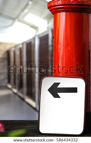 white blank sign with black arrow and red post office box in front of a toilet. Blank screen with copy space