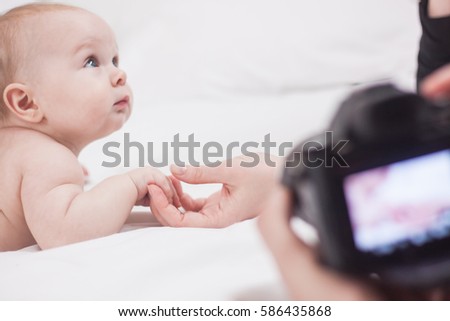 Close up picture of photographer at work with cute baby in white bed 