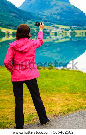 Tourism and travel. Woman tourist taking photo with camera, enjoying fjord mountains view, Sogn og Fjordane county. Norway Scandinavia.