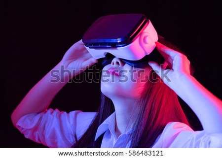 Asian Chinese young woman using virtual reality smart glasses watch movie.low key photo