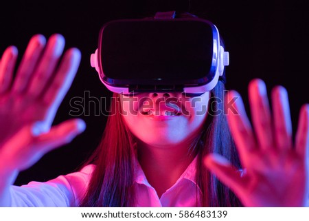 Asian Chinese young woman using virtual reality smart glasses play game.low key photo